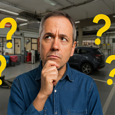 Homem de meia-idade, com expressão de dúvida, olhando para o alto em uma oficina mecânica, com pontos de interrogação ao redor, simbolizando indecisão sobre manutenção automotiva.