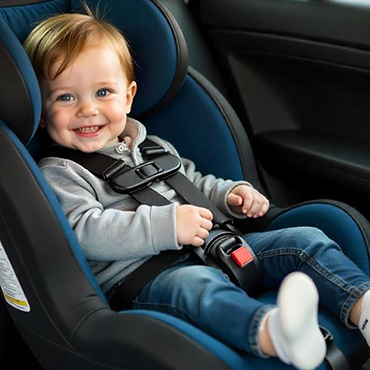 Bebê sorridente sentado com segurança em uma cadeirinha infantil instalada corretamente no banco traseiro do carro com sistema ISOFIX.